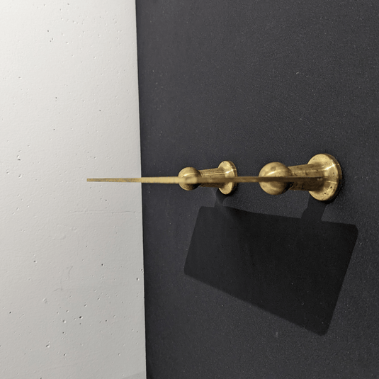 Side on view of brass shelf on black wall